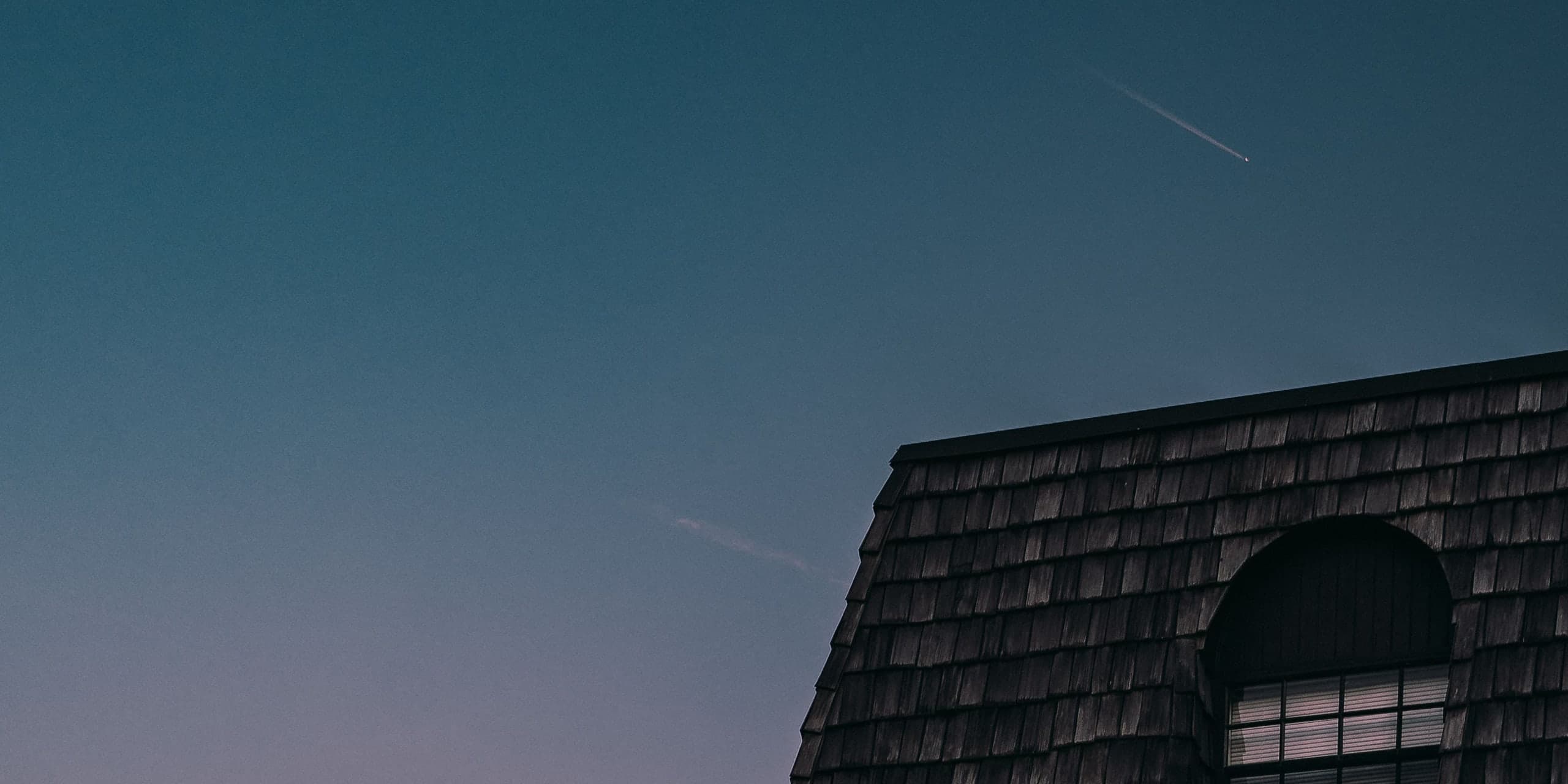 Shingled rooflines against a deep blue and violet dusk sky
