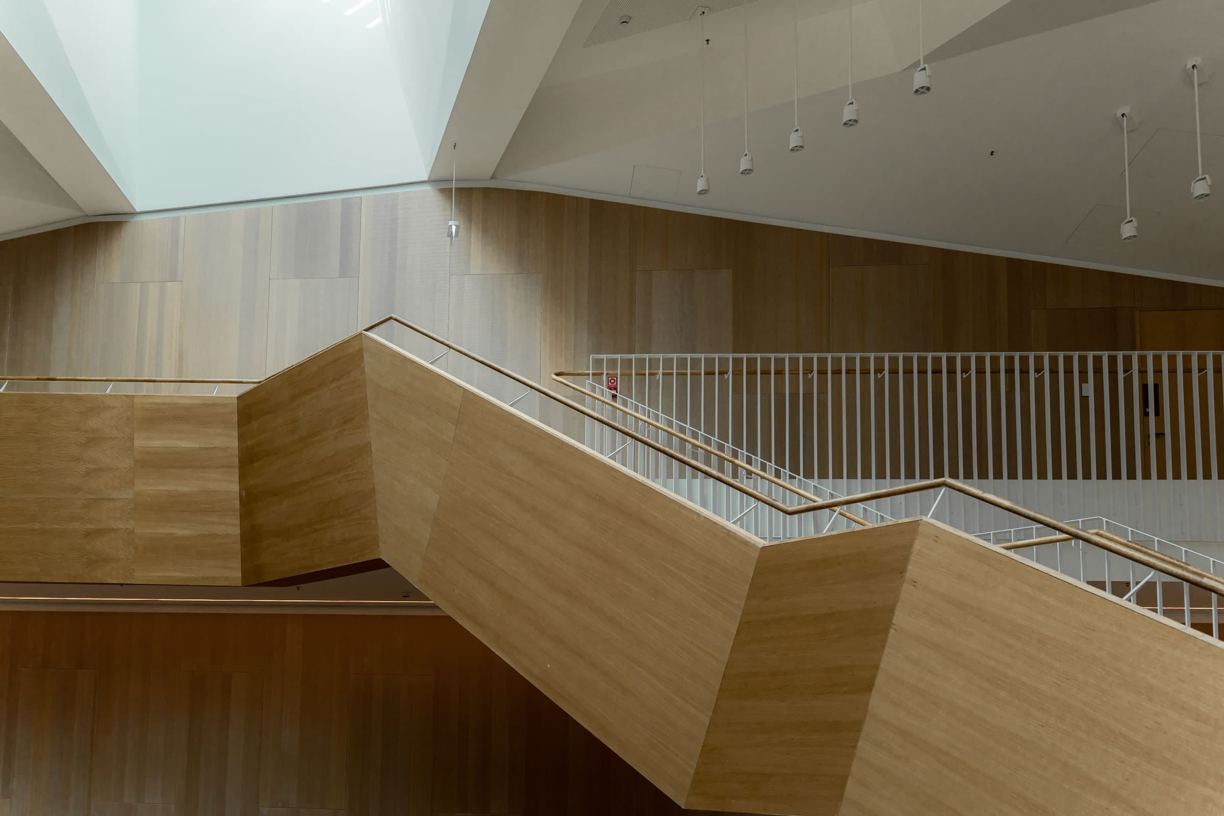 Sculptural oak staircase turning under a skylight