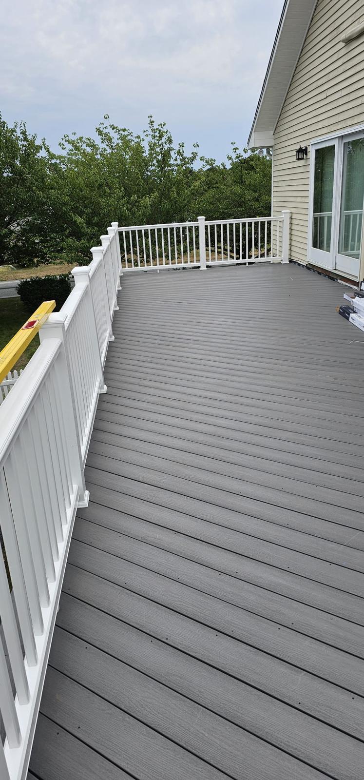 Composite grey deck with a white railing beside a shingled house