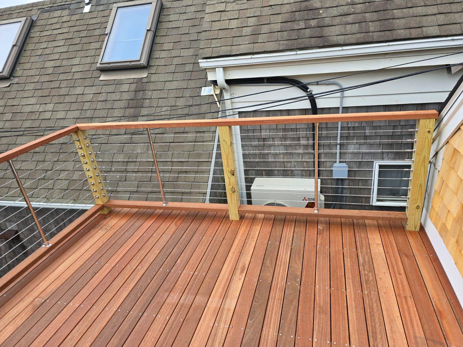 Mahogany deck with a stainless cable railing against a cedar-shingle wall