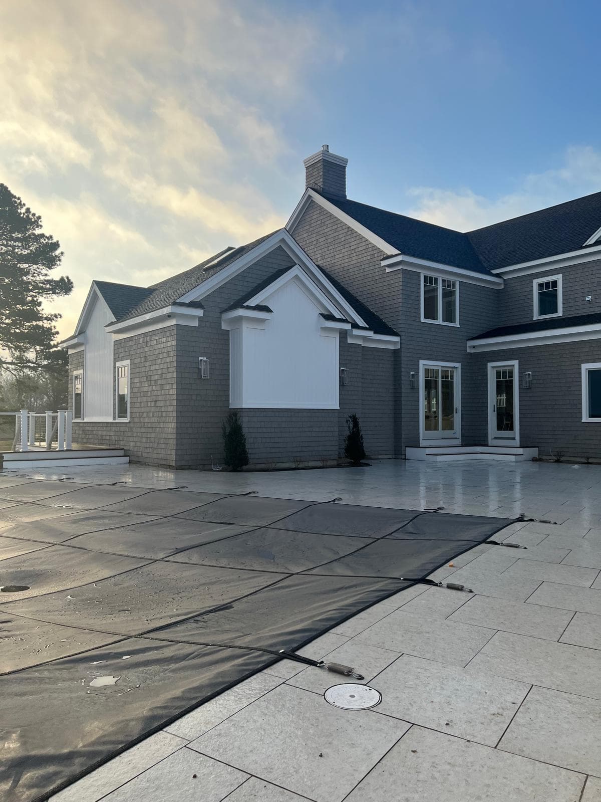 Shingle style residence and stone pool terrace at dusk