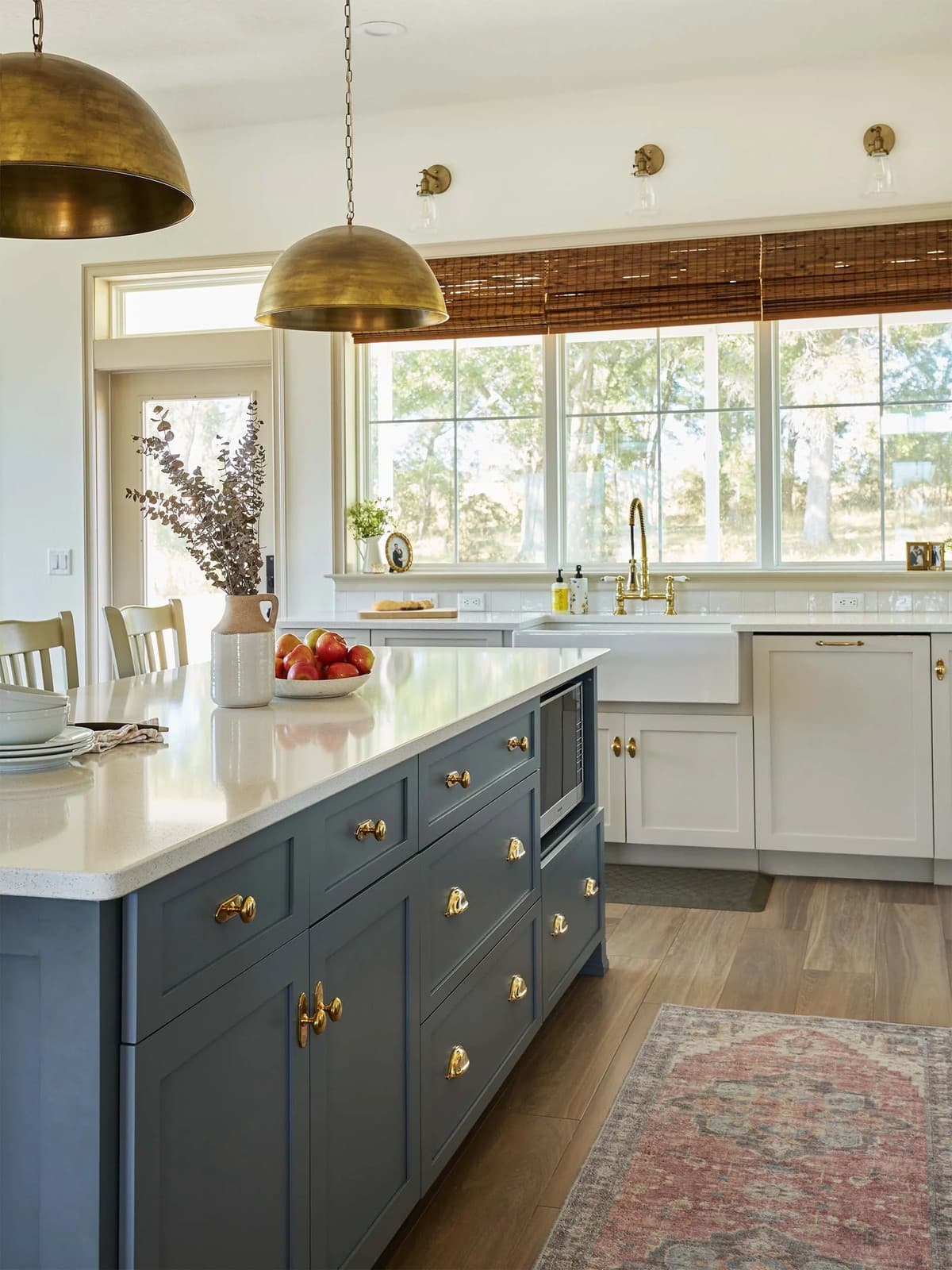 Custom kitchen with a blue island, brass hardware and a farmhouse sink