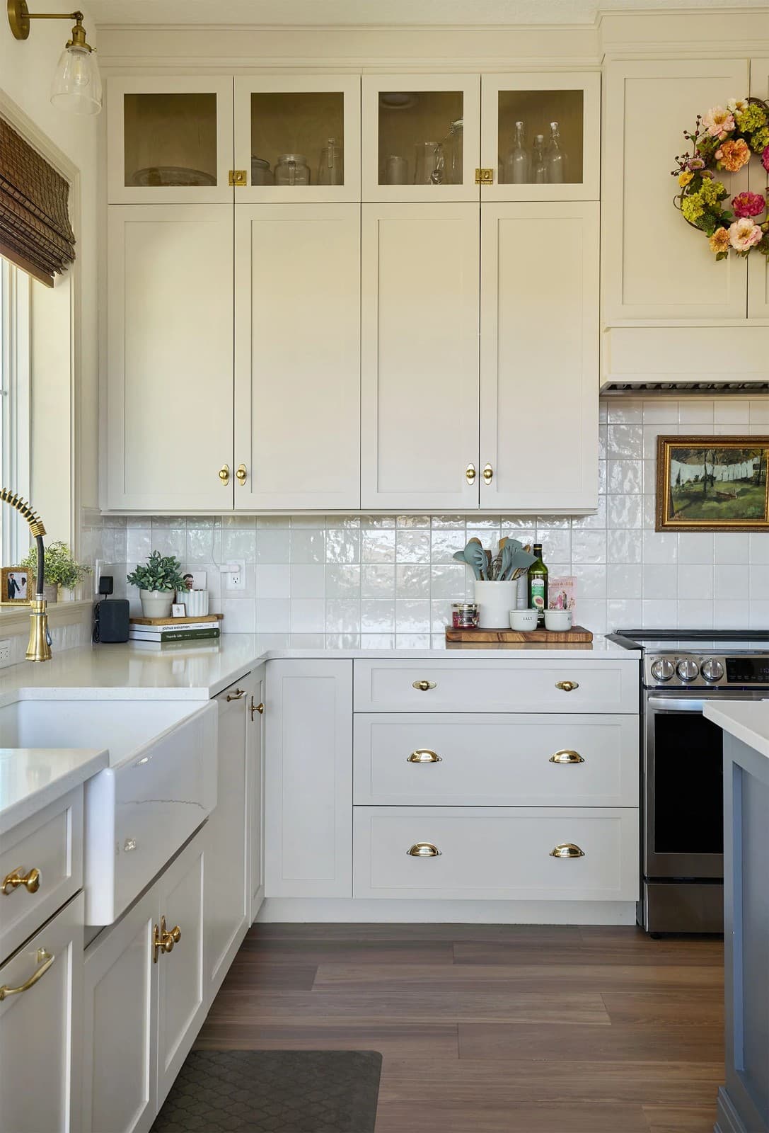 White kitchen with glass upper cabinets, subway tile and brass hardware