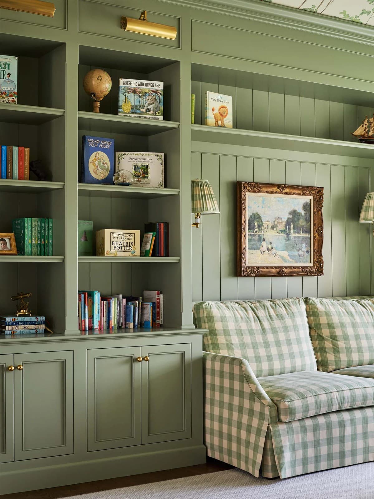 Built-in library wall with sage-green cabinetry, shelving and panelled millwork